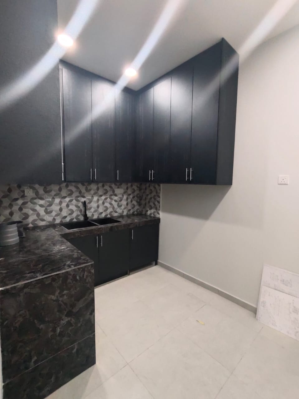 Kitchen corner with dark wall and base cabinets, patterned splashback and double sink